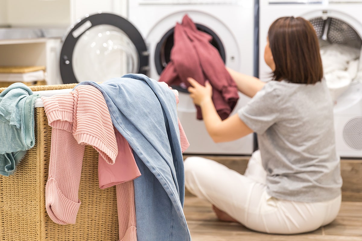 mulher colocando roupa na máquina de lavar